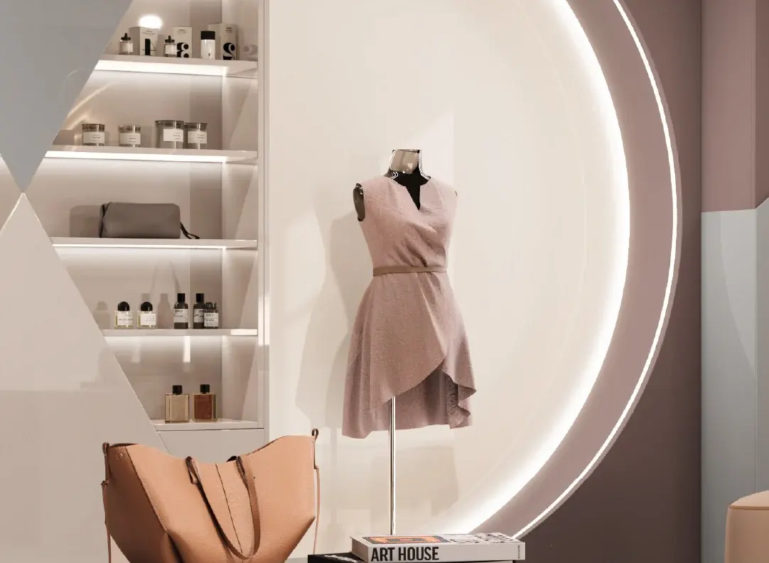 Vidriera de un local de ropa: un maniquí con vestido rosa, estantes iluminados con perfumes y una cartera, y un gran arco de luz sobre la pared de fondo, en tonos rosados y blancos.